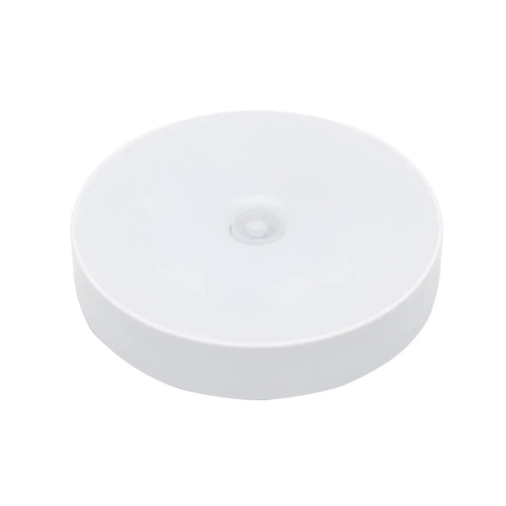 Small white USB rechargeable motion sensor LED night light with adhesive tape for mounting.