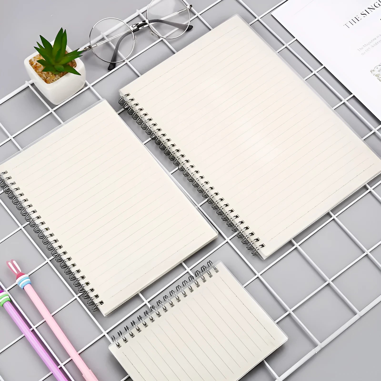 Coil-bound notebook with grid dot matrix ruling in A6, A5, and B5 sizes on a desk.