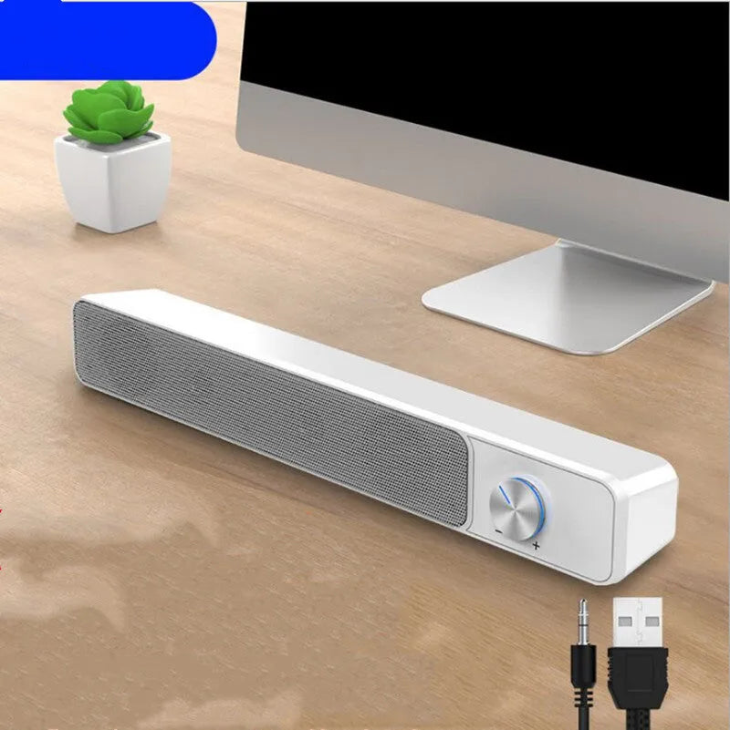 Black and white compact USB-powered desktop computer speaker on a wooden desk