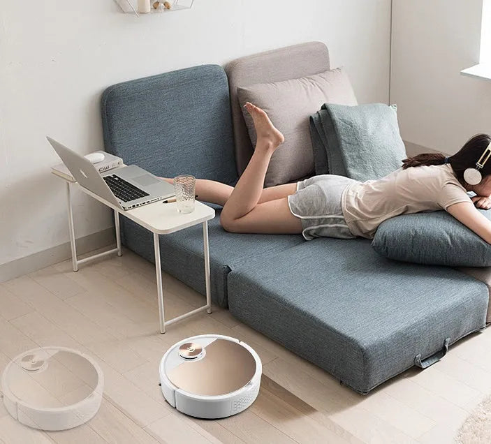 Golden and silver intelligent robot vacuum cleaner with remote control on hardwood floor