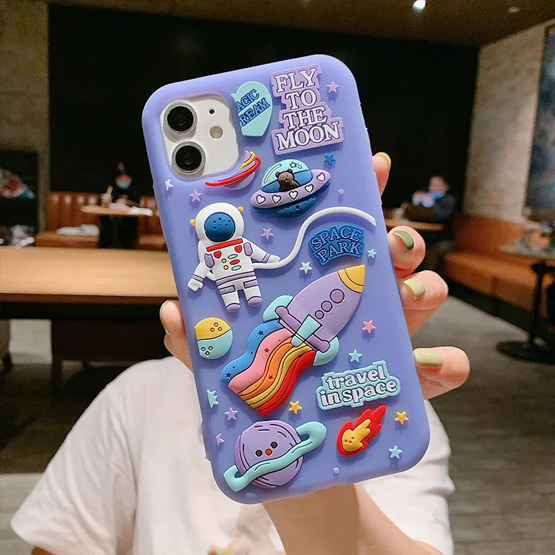 Purple silicone iPhone case with a cartoon astronaut design, shown fitted on a phone.