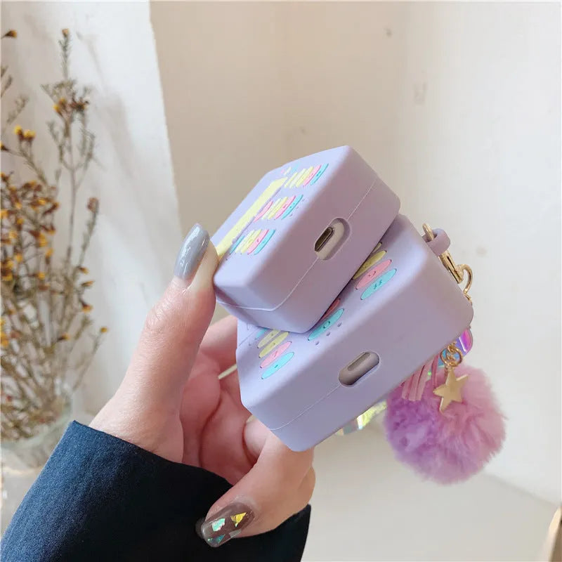 Purple silicone protective case for Apple AirPods with a small white fur ball pendant attached.