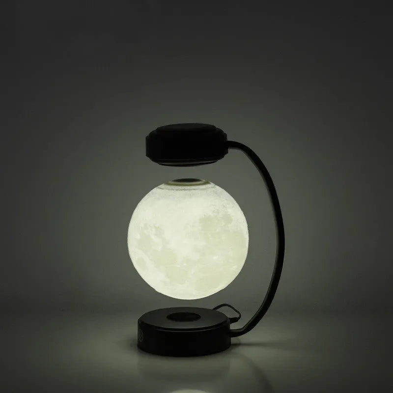 Black magnetic levitation moon lamp floating above its base with warm golden light.
