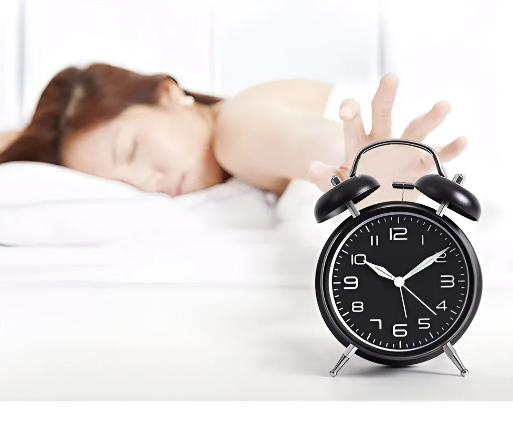 Large black metal alarm clock with luminous display and silent sweep movement on a bedside table