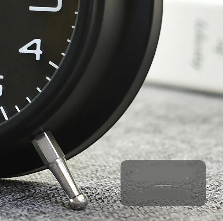 Large black metal alarm clock with luminous display and silent sweep movement on a bedside table
