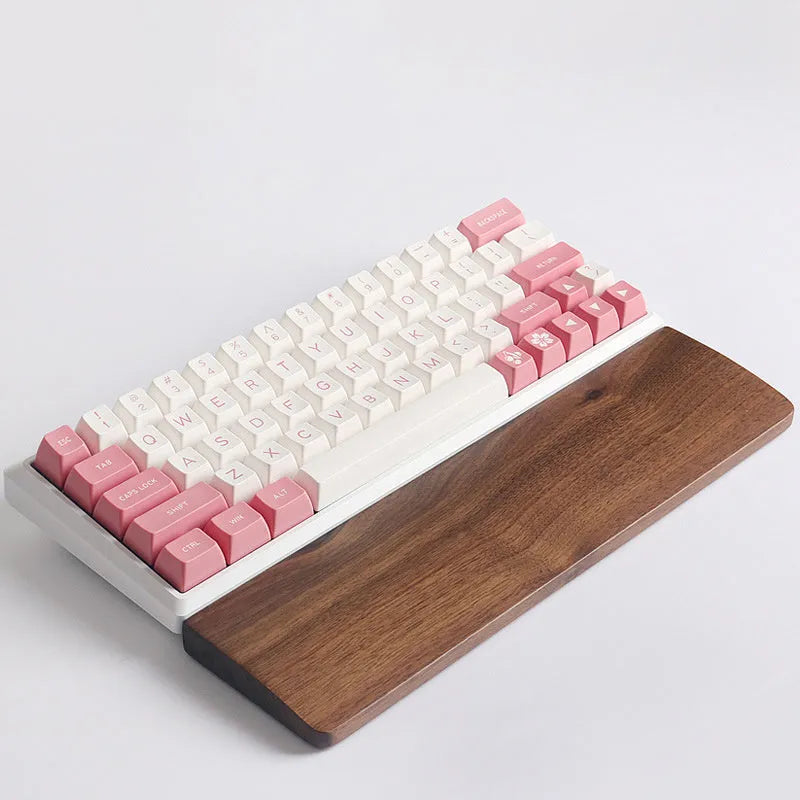 Solid walnut wood wrist rest for a mechanical keyboard on a desk.