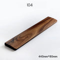 Solid walnut wood wrist rest for a mechanical keyboard on a desk.