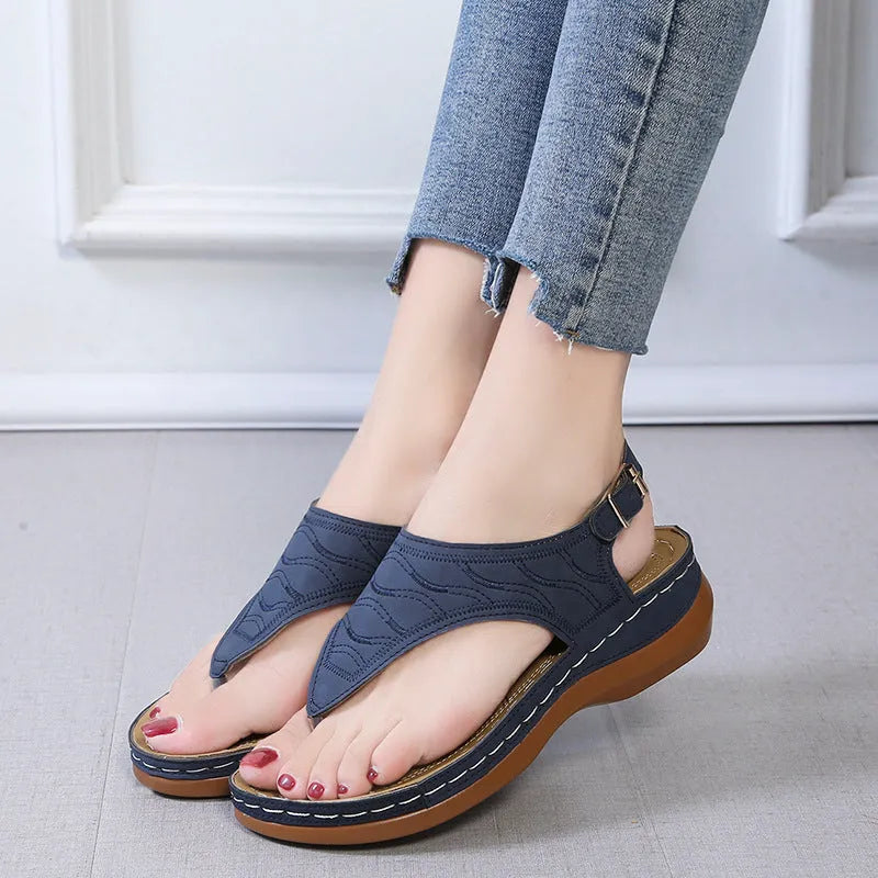 Women's red wedge heel sandals with an adjustable buckle strap on a plain background.