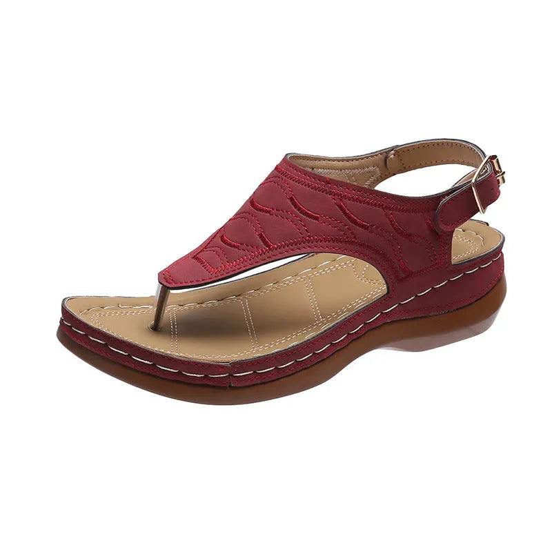 Women's red wedge heel sandals with an adjustable buckle strap on a plain background.