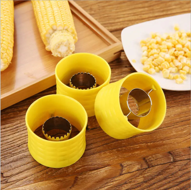 Yellow manual corn thresher with corn-kernel-shaped design on a kitchen counter.