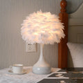 Nordic feather bedside lamp with white hand-woven fur shade and iron base on a wooden table.