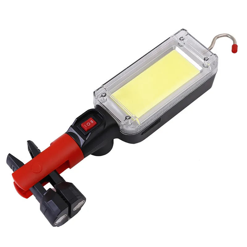 Red portable USB rechargeable COB camping lamp with magnetic hook on a metal surface.