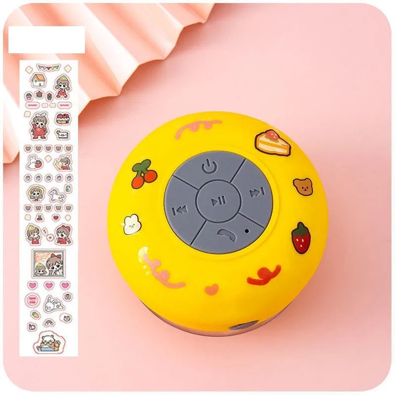 Colourful waterproof Bluetooth mini speaker with a suction cup base mounted on a tiled wall.