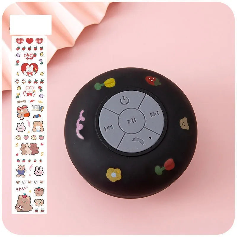 Colourful waterproof Bluetooth mini speaker with a suction cup base mounted on a tiled wall.