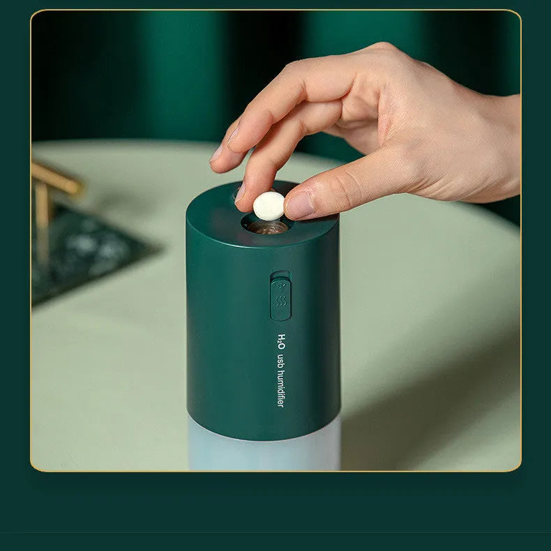 Blue columnar USB desktop humidifier with water tank and aromatherapy function on a wooden table.