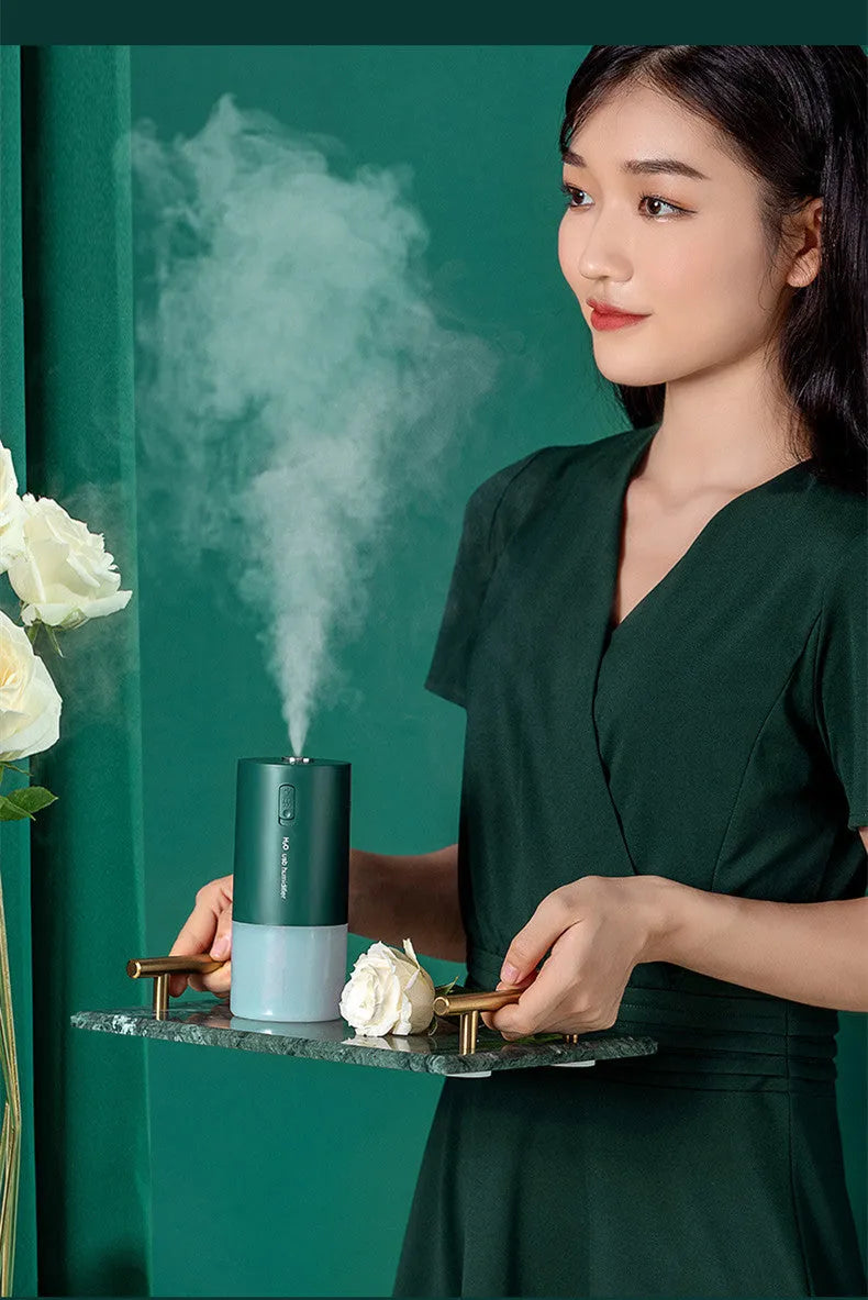 Blue columnar USB desktop humidifier with water tank and aromatherapy function on a wooden table.