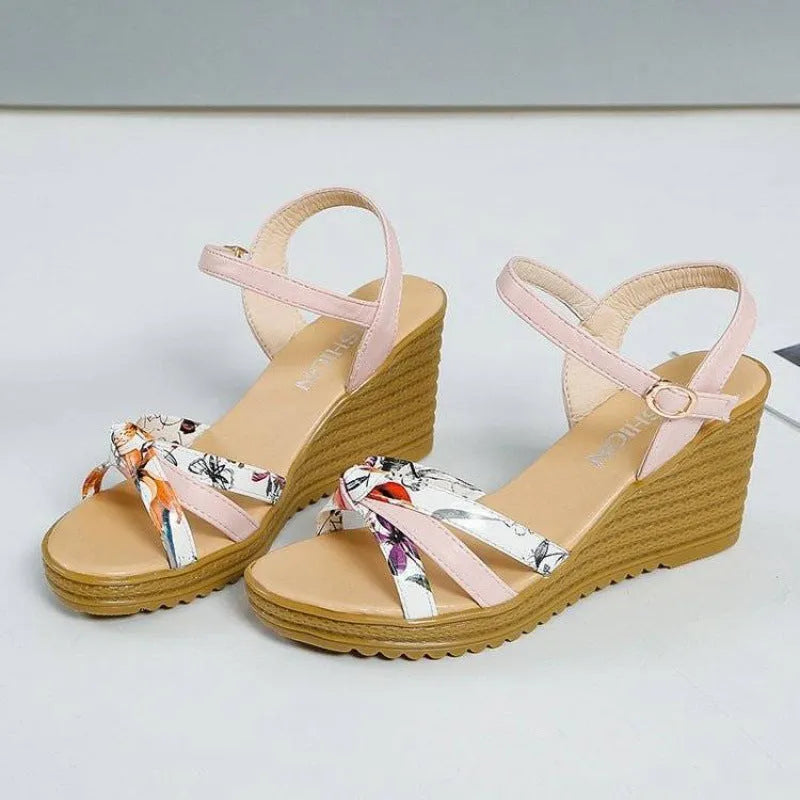 Pink women's wedge sandals with a thick heel, fish mouth opening, and a buckle strap.