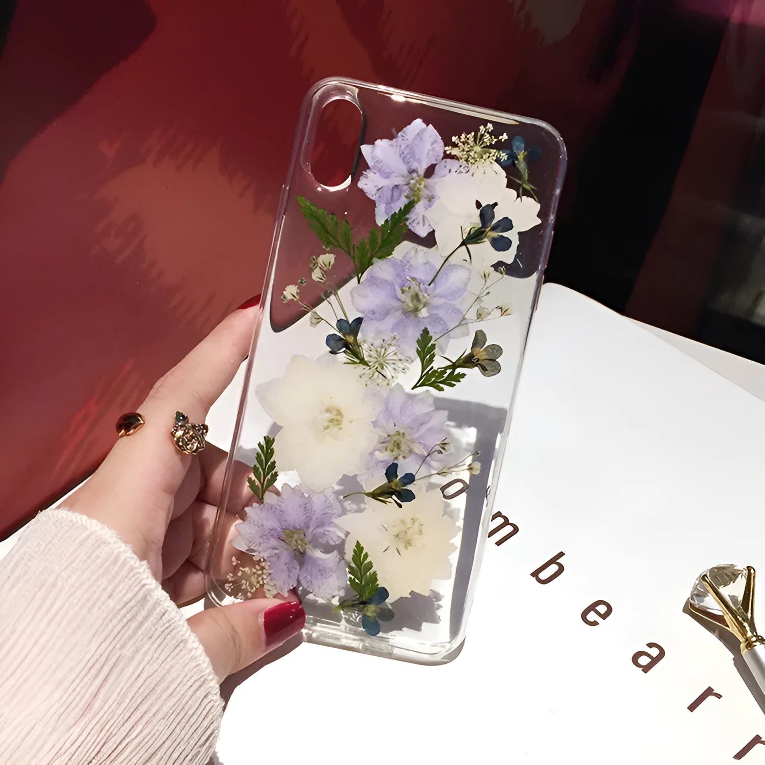 Soft blue and purple dried floral bouquet design on a transparent TPU case for an iPhone.