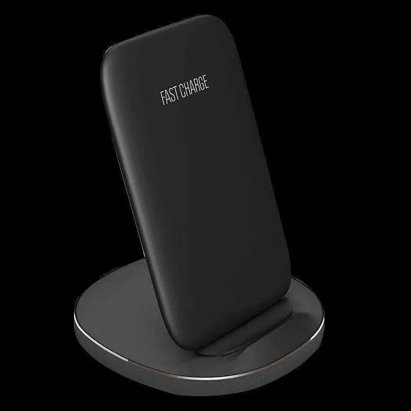 A white minimalist vertical wireless charging stand holding a smartphone upright on a desk.