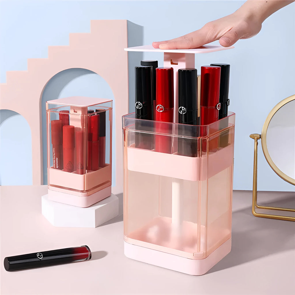 Press-lift lipstick storage box with clear lid and internal grids, shown in pink on a desktop.