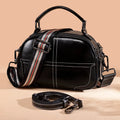 Round women's leather handbag with soft handles and zipper in multiple colours.