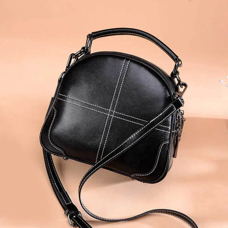 Round women's leather handbag with soft handles and zipper in multiple colours.