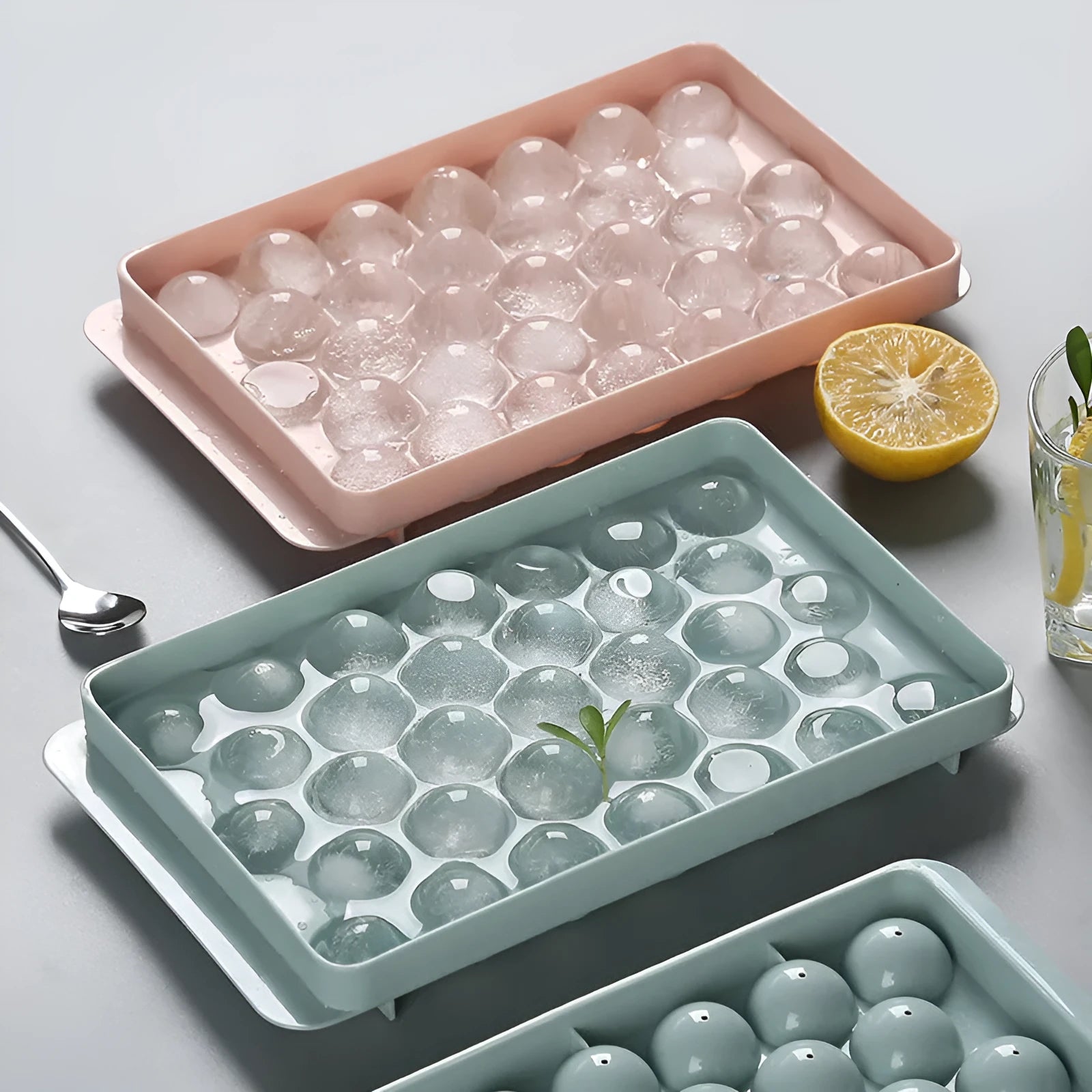 Sky blue and pink 3D round ice cube mould trays showing spherical cavities.