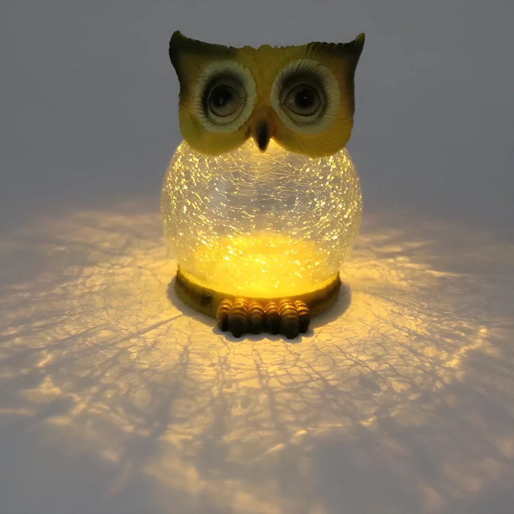 White solar powered LED owl shaped outdoor light on a garden patio.