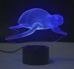 Small black-based 3D acrylic LED table lamp showing colourful gradient light effect on a desk.