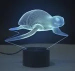 Small black-based 3D acrylic LED table lamp showing colourful gradient light effect on a desk.