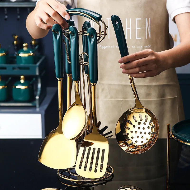 Seven stainless steel kitchen utensils including spatula, turner, ladle, slotted spoon, and pasta server