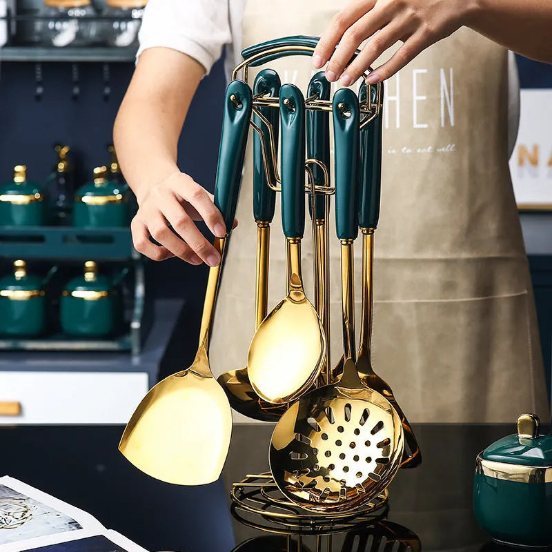 Seven stainless steel kitchen utensils including spatula, turner, ladle, slotted spoon, and pasta server