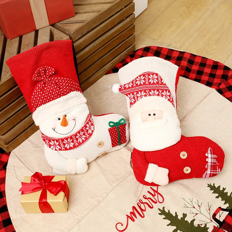 Large red and white knitted Christmas stocking with Santa Claus design hanging on a fireplace.