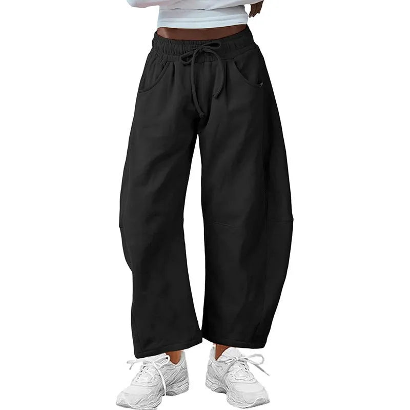Women's loose cropped sweatpants in apricot colour with drawstring waist and side pockets on a neutral background.