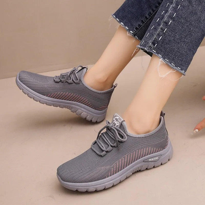 Women's black casual sneakers with mesh upper, cross straps, and round toe on a rubber sole.