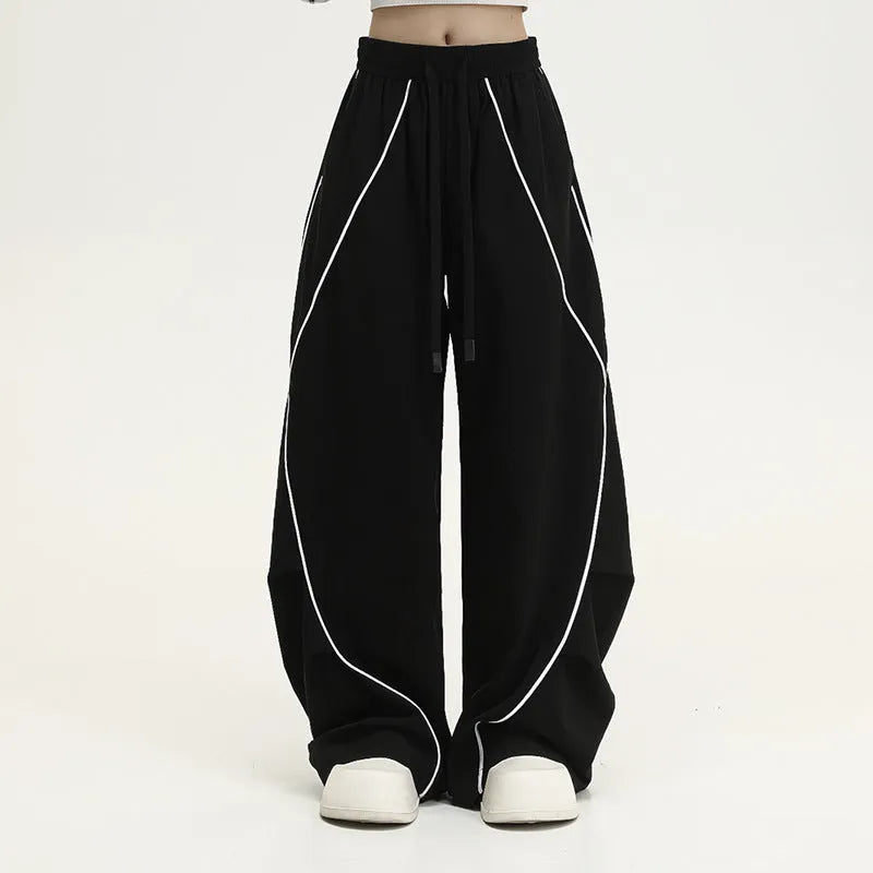Black striped wide-leg sports pants with pleated detail on a mid-waist, loose fit.
