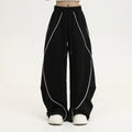 Black striped wide-leg sports pants with pleated detail on a mid-waist, loose fit.