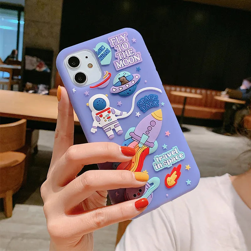 Purple silicone iPhone case with a cartoon astronaut design, shown fitted on a phone.