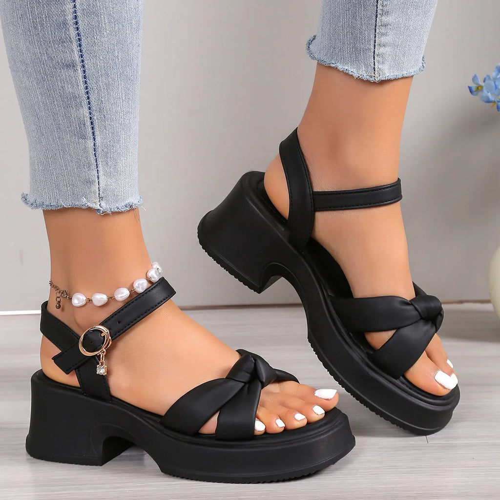 Black high-heel slippers with a thick rubber sole and a button fastening over the instep.