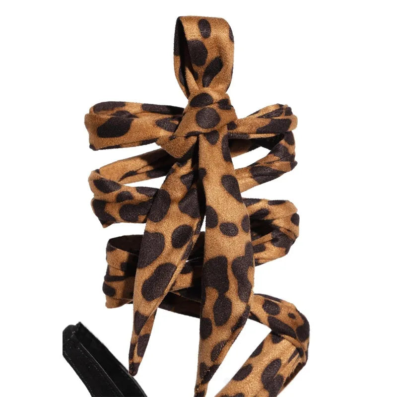 Light brown leopard print women's high-heeled sandals with cross-straps and a tall slender heel.