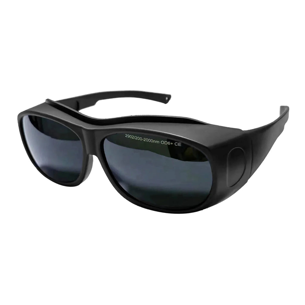 A pair of clear laser and welding safety goggles with a soft cleaning cloth on a dark background.