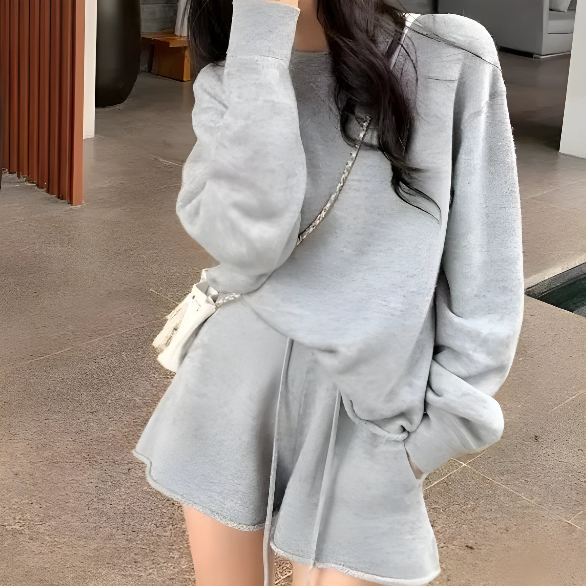 Woman wearing a loose grey long sleeve knitted sweater and matching wide leg shorts set.
