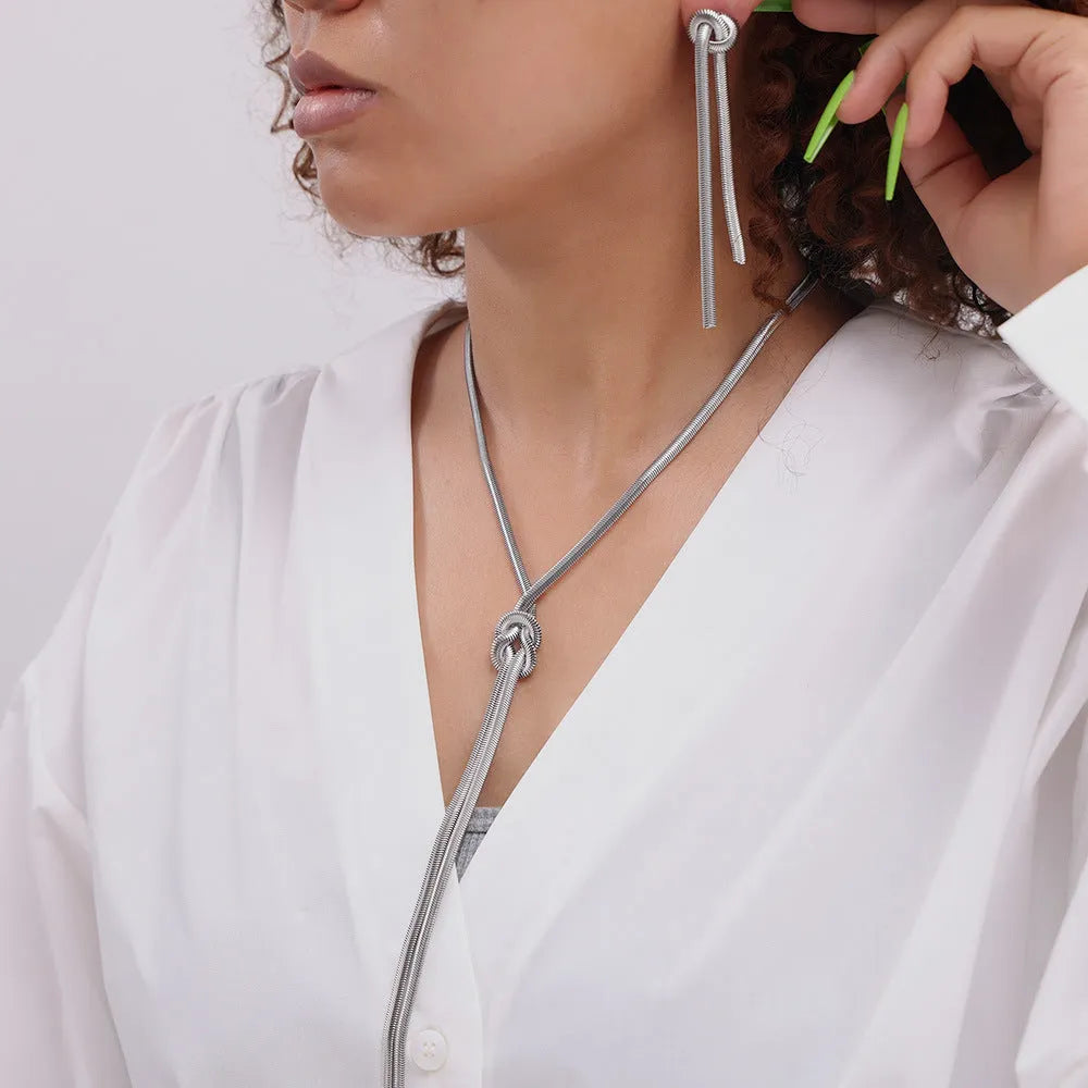 Gold plated titanium steel necklace with snake chain and knotted tassel pendant, shown with matching earrings.