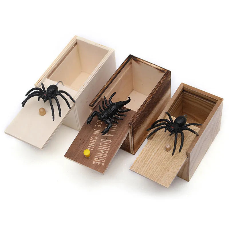 Wooden prank scare box open showing a lifelike spider figurine on a spring, next to the box lid.