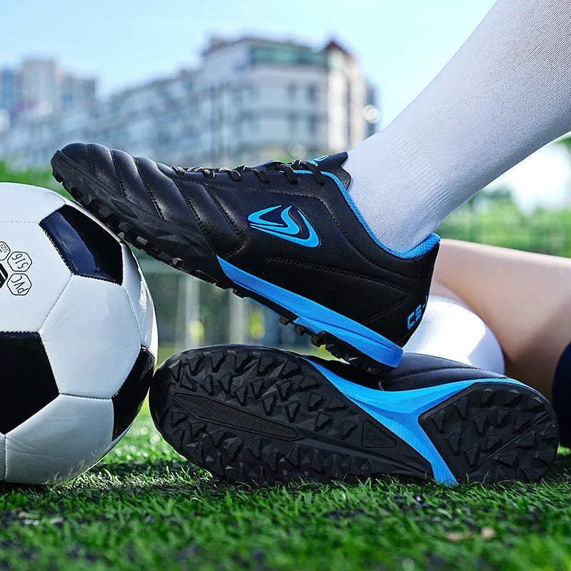 Low top football shoes with synthetic leather upper and rubber sole in black and white broken nails colour.