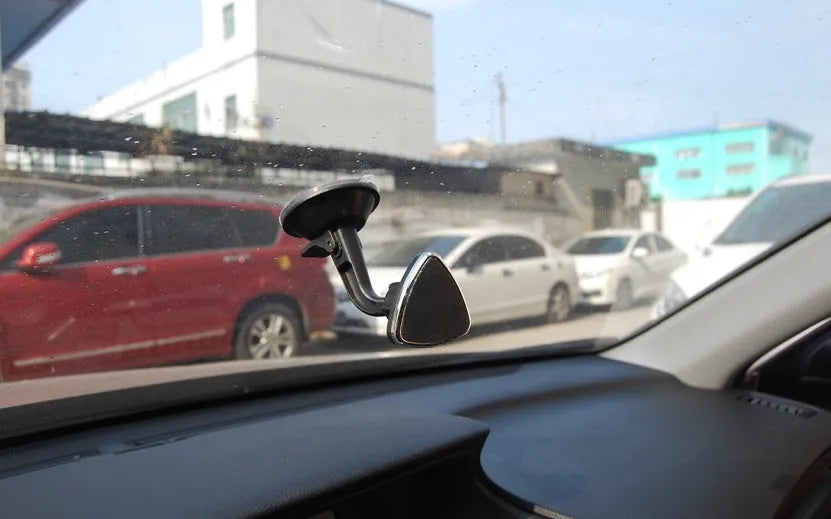 Black magnetic car phone holder with 360-degree rotating bracket mounted on a car dashboard.