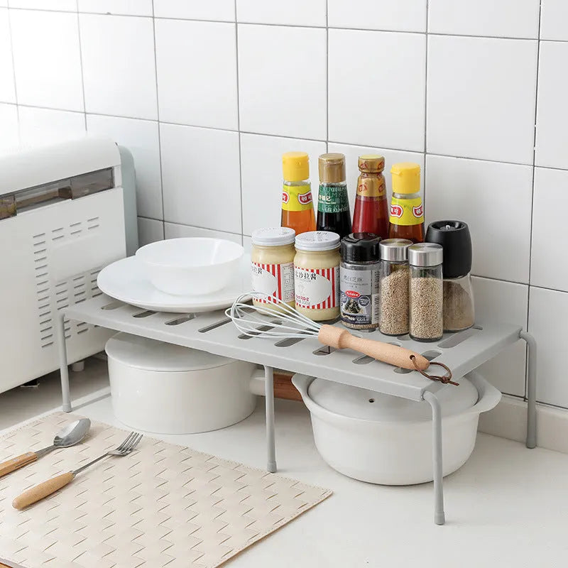 White telescopic kitchen storage rack with adjustable height on a countertop
