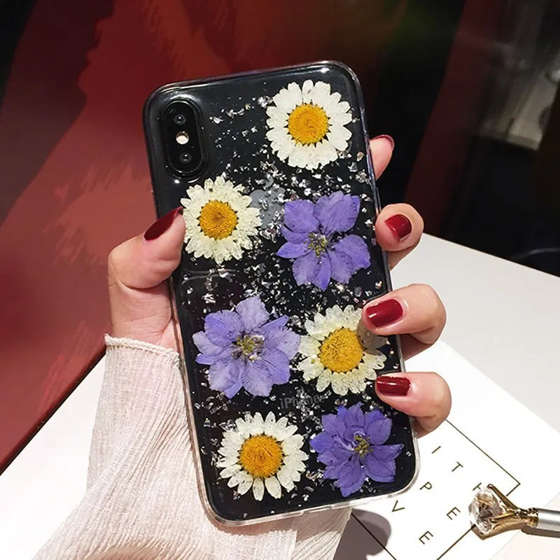 Clear soft TPU iPhone case with pink dried flowers preserved in epoxy resin on the back.