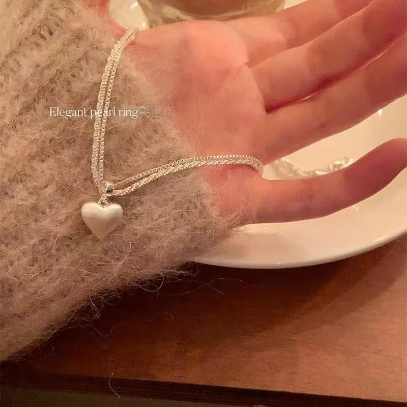 Double-layer heart pendant necklace in brushed silver finish with adjustable chain