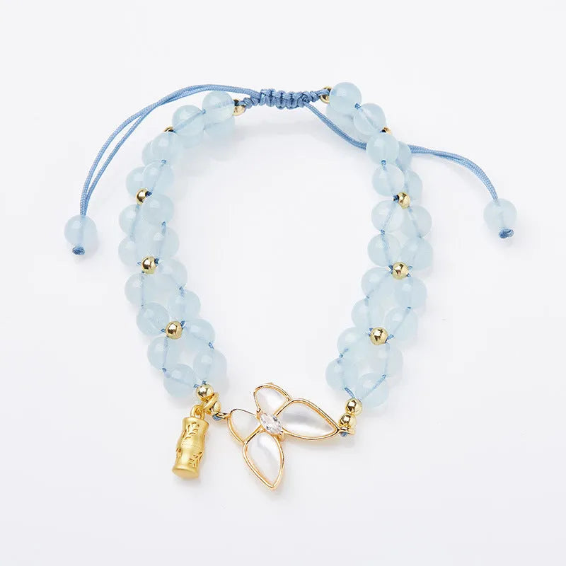 Women's woven bracelet with 6mm aquamarine beads and butterfly design on a wrist.